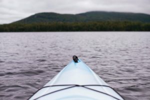 The front of a blue kayak on a lake.