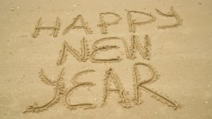 Happy New Year written in sand on the beach.